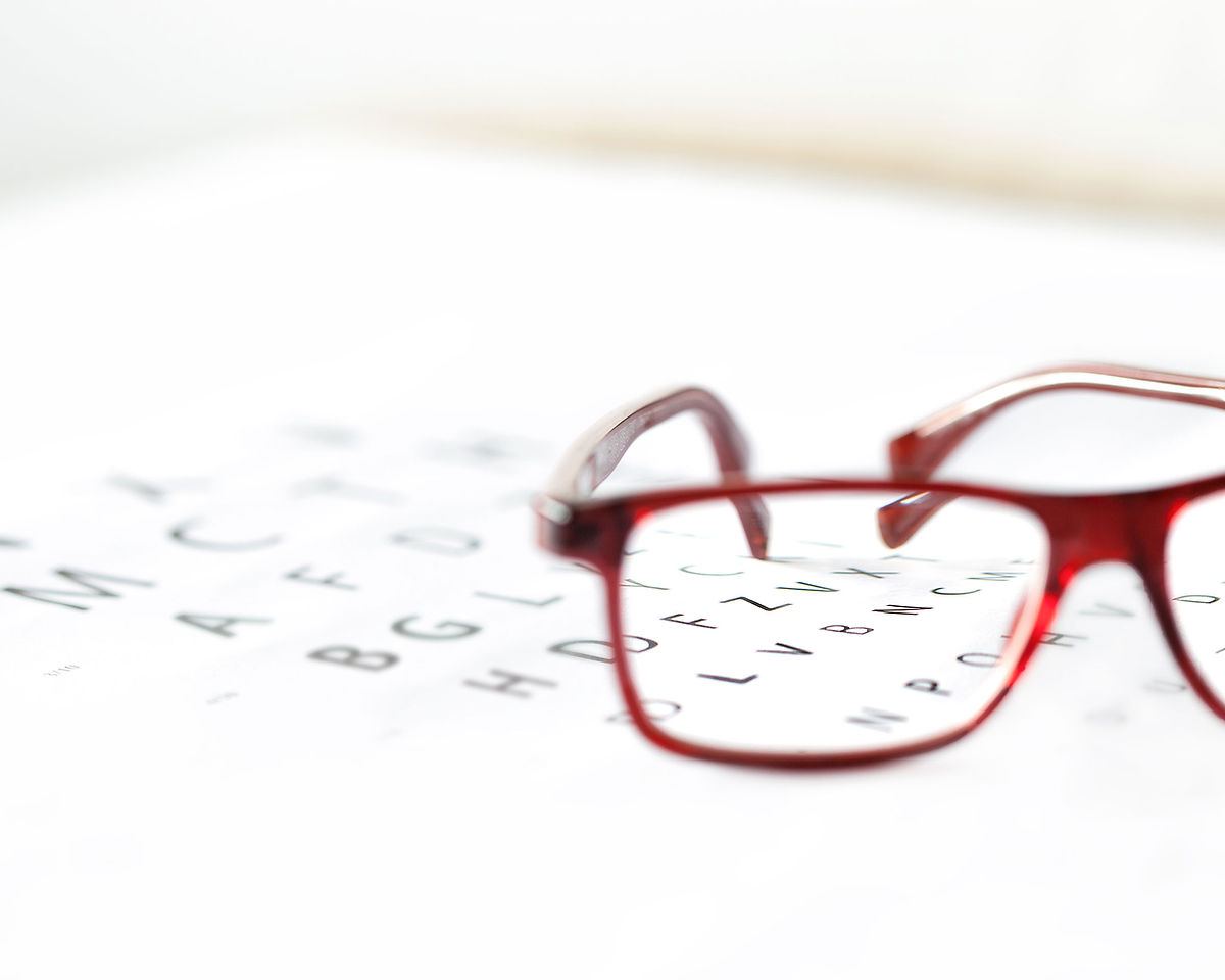 Red glasses resting on an eye chart