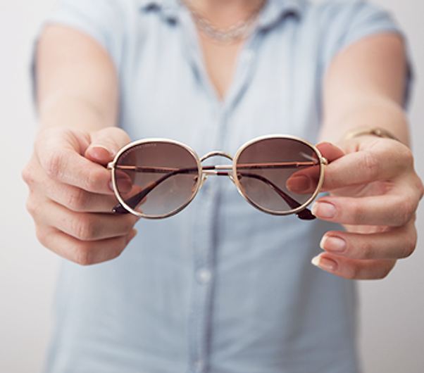 Hands holding out a pair of sunglasses